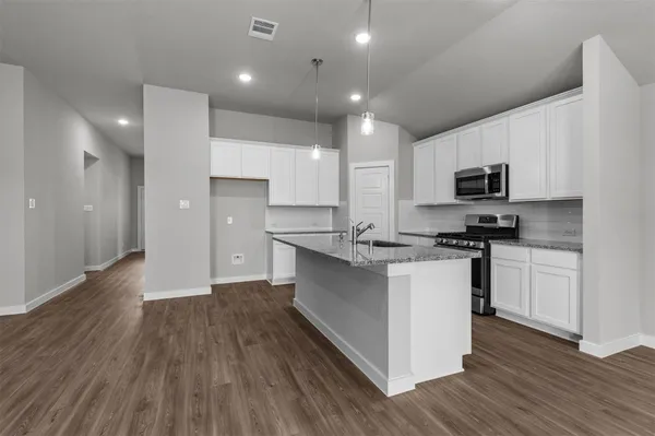 a kitchen with granite countertop a sink cabinets and stainless steel appliances
