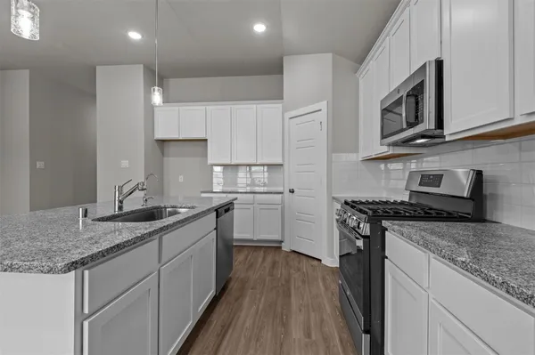 a kitchen with stainless steel appliances granite countertop a sink stove and microwave
