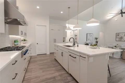 a large white kitchen with a sink and a stove top oven