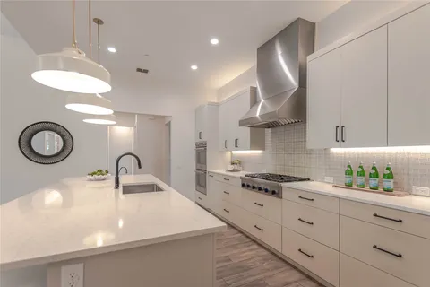 a kitchen with stainless steel appliances granite countertop a sink a stove and a wooden floors