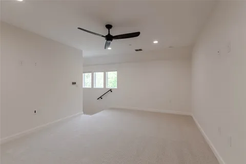 an empty room with a ceiling fan and window