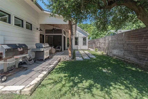 a view of a backyard with table and chairs potted plants and a large tree