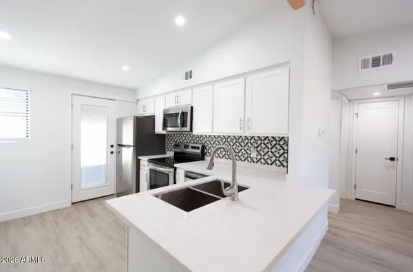 a kitchen with a refrigerator a stove top oven a sink dishwasher and wooden floor