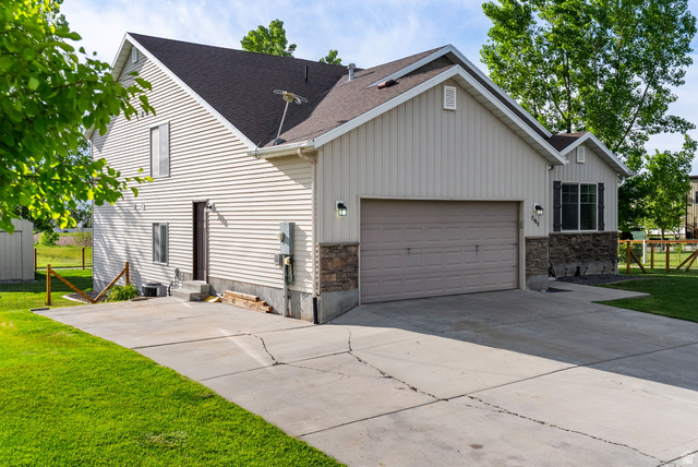 2485 South 1100th Street West Logan, UT 84321 - Photo 4 of 53 Exterior featuring light-colored horizontal siding, a dark roof, and a two-car garage with a complementary door
