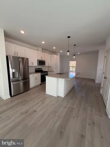 a view of kitchen with kitchen island wooden floor stainless steel appliances and cabinets