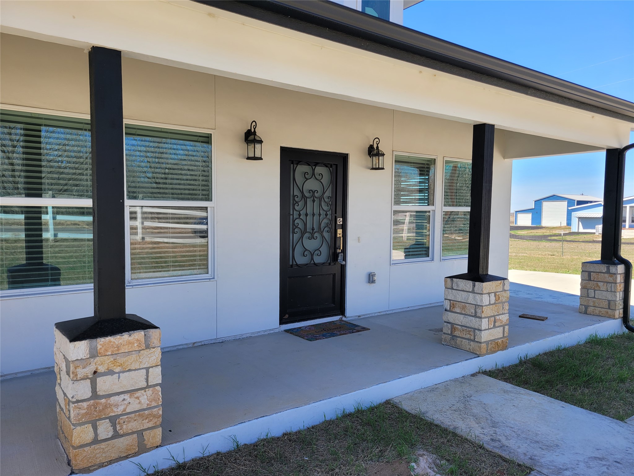 422 County Road 422 Road Stockdale, TX 78160 - Photo 3 of 37 A welcoming front porch features stone-clad columns and an ornate entry door.