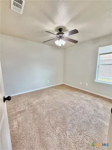 an empty room with a window and a ceiling fan