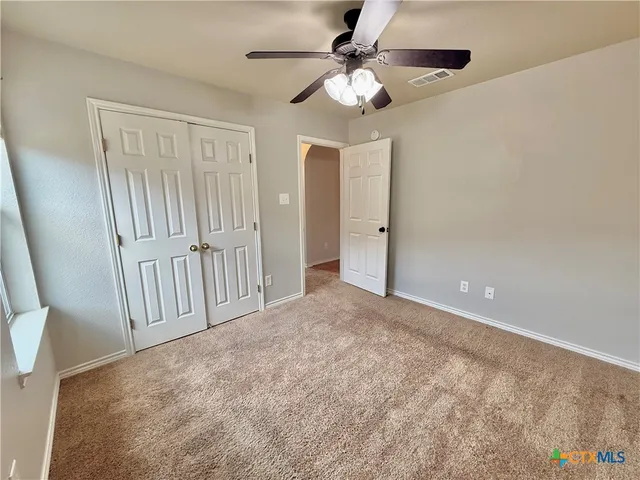 an empty room with windows and fan