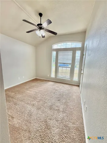 an empty room with windows and ceiling fan