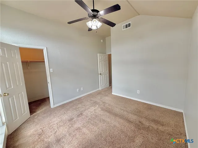 an empty room with closet and a ceiling fan