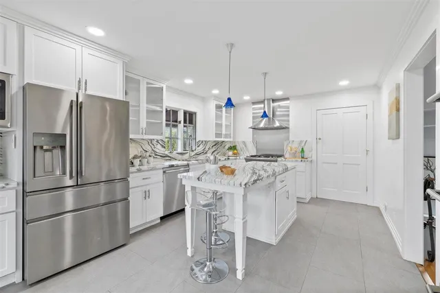 a kitchen with granite countertop white cabinets and stainless steel appliances