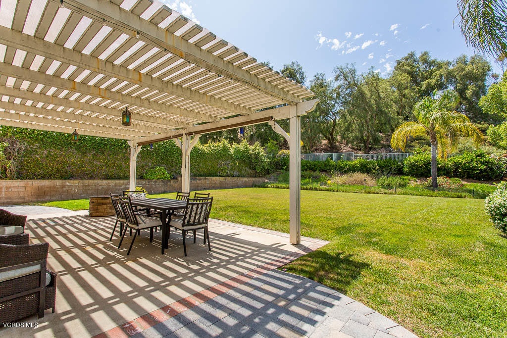 3877 Sunsetridge Road Moorpark, CA 93021 - Photo 22 of 30 a view of a patio with dining table and chairs under an umbrella with a small yard