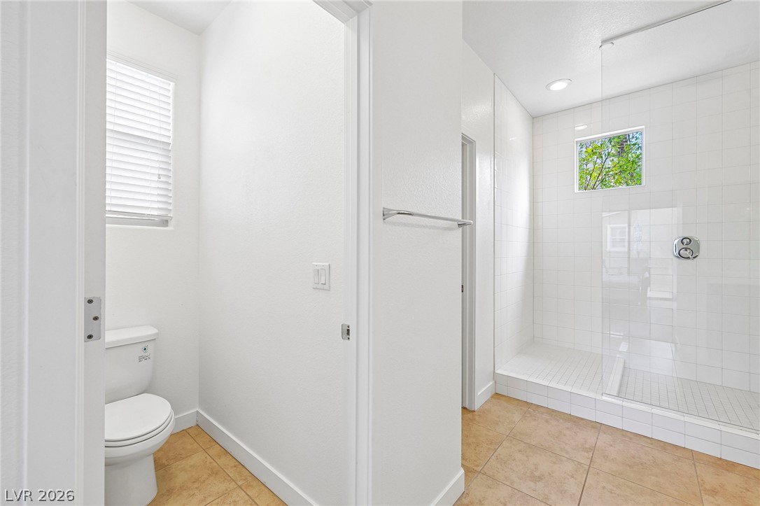 1100 East Sunset Road Henderson, NV 89011 - Photo 28 of 63 Tiled floors and a glass-enclosed walk-in shower define this bright bathroom space.