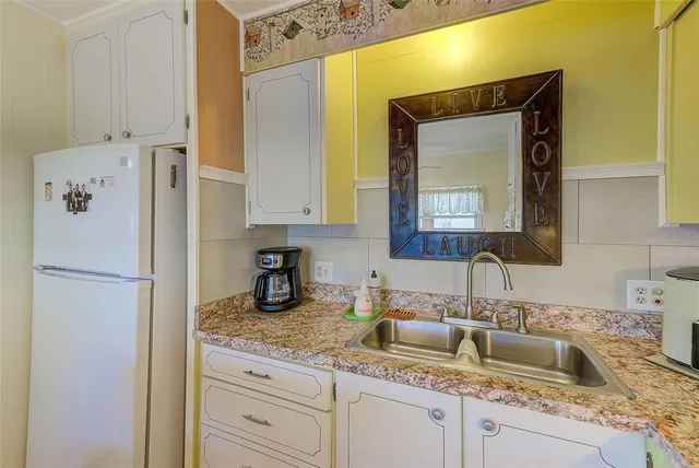 a white kitchen with sink stainless steel appliances and a counter space