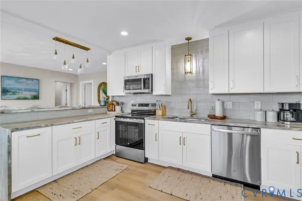a kitchen with granite countertop white cabinets sink and stainless steel appliances