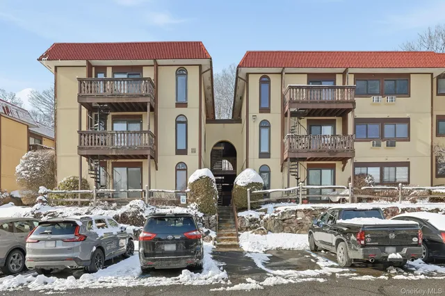 a front view of a building with cars parked