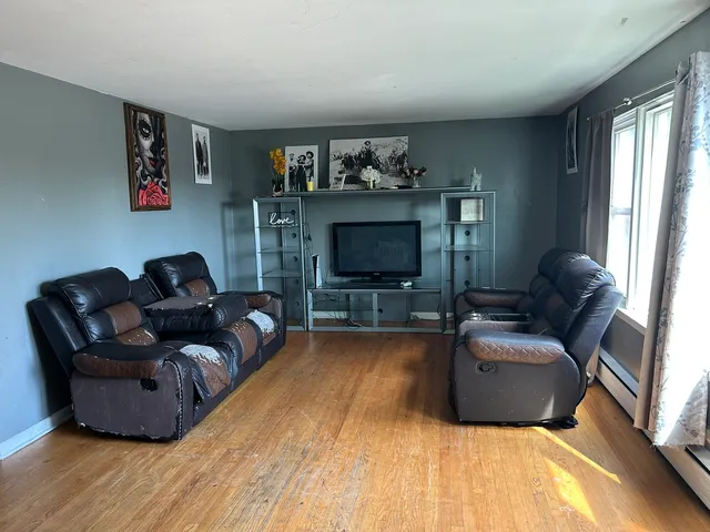a view of an empty room with a window and wooden floor