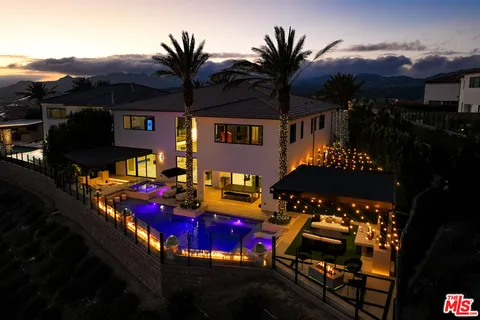 a dining hall with stainless steel appliances kitchen island granite countertop a table chairs and a view of living room