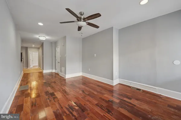 an empty room with wooden floor and a ceiling fan