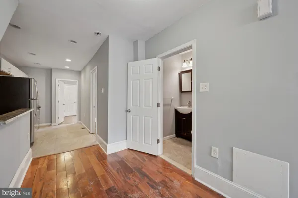 a view of a hallway with wooden floor and a bathroom