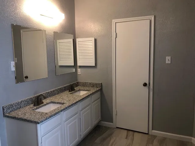a bathroom with a granite countertop sink and a mirror
