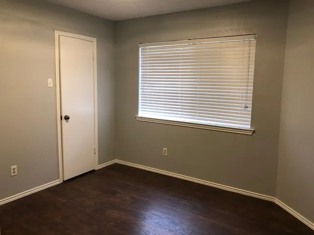an empty room with wooden floor and a window