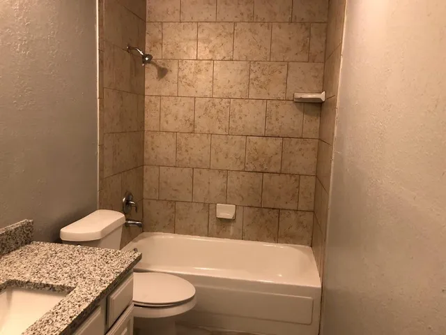 a bathroom with a granite countertop bathtub and toilet