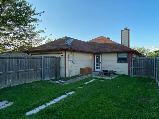 a view of a house with backyard and wooden fence