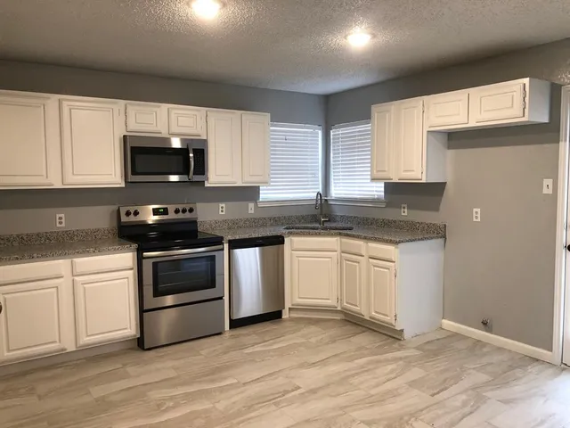 a kitchen with granite countertop a sink and steel appliances