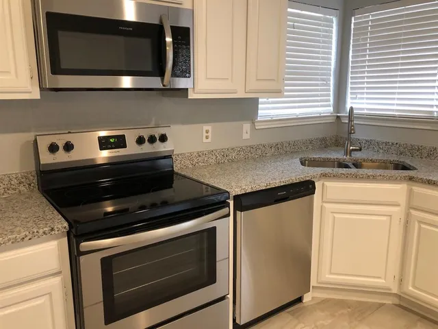 a kitchen with granite countertop a stove microwave and sink