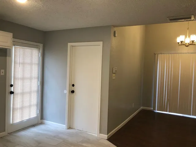 a view of a hallway with wooden floor and a bathroom