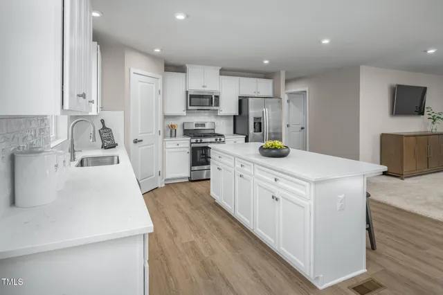 a kitchen with stainless steel appliances granite countertop a table chairs sink refrigerator and cabinets