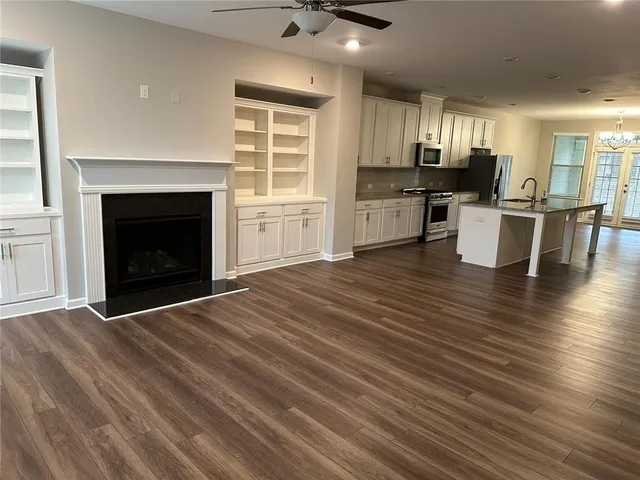 a open kitchen with granite countertop a stove top oven a sink dishwasher a dining table and chairs with wooden floor