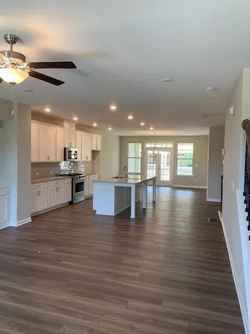 a view of an empty room with wooden floor and a kitchen