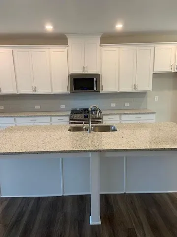 a kitchen with granite countertop a sink a stove a microwave and cabinets