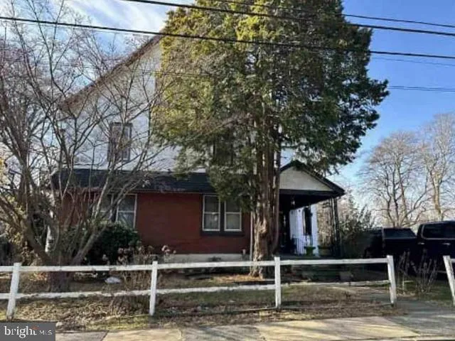 a view of a house with wooden fence and large trees