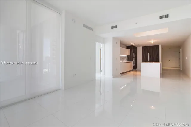 a view of a hallway with wooden floor and a kitchen