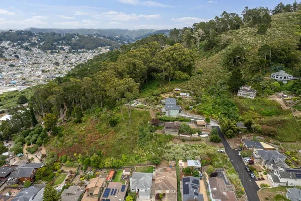 an aerial view of residential houses with outdoor space and trees all around