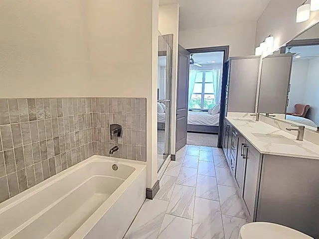 a bathroom with a tub a sink and a large mirror