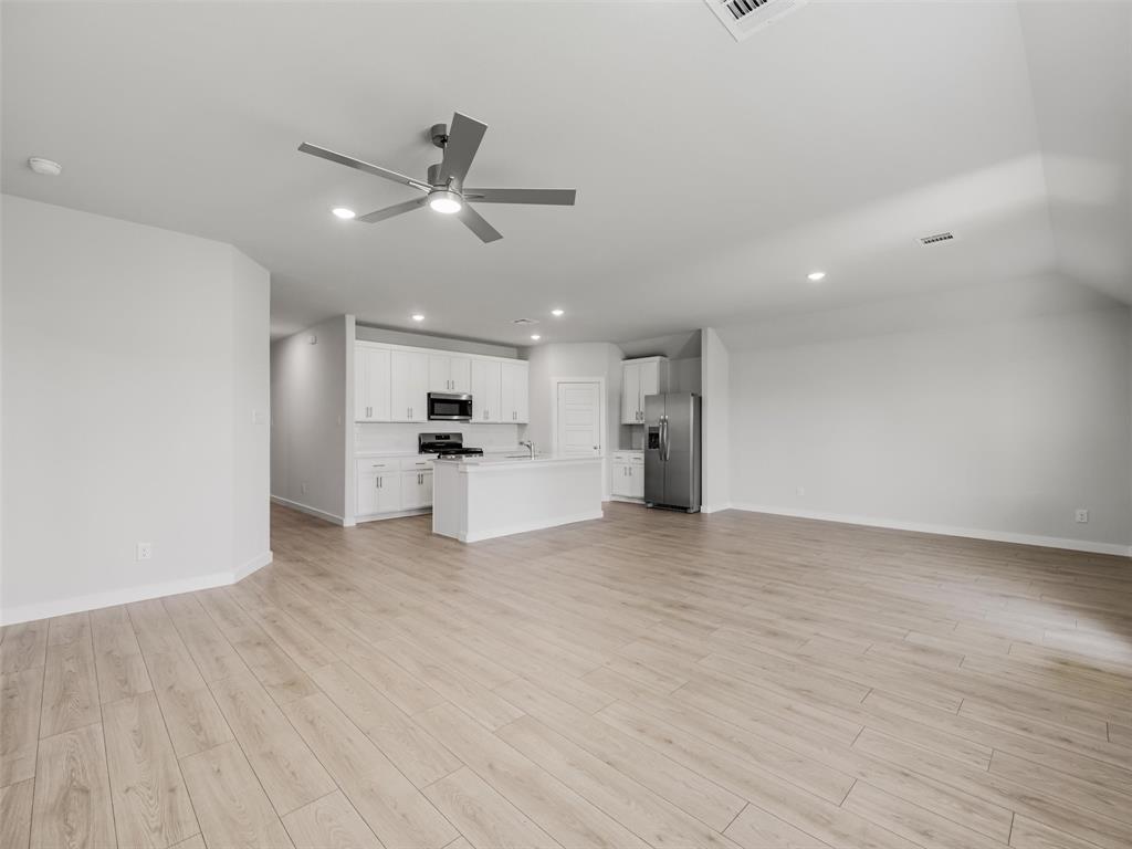 1136 Del Rio Drive Lavon, TX 75166 - Photo 12 of 30 Open-concept living space featuring engineered wood-finish flooring throughout, recessed lighting, and a modern ceiling fan with integrated light fixture