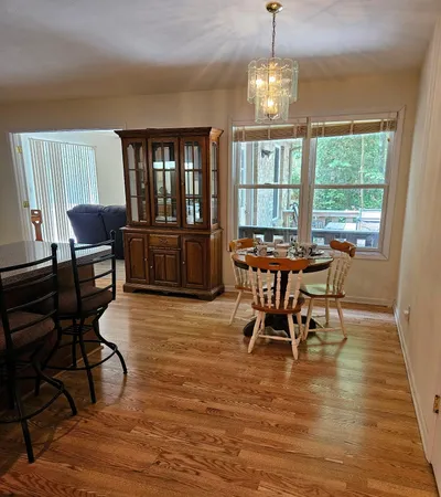 a dining room with wooden floor a chandelier a glass table and chairs