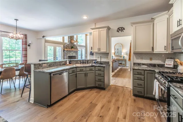 a kitchen with stainless steel appliances granite countertop a stove a sink dishwasher a refrigerator and a dining table with wooden floor