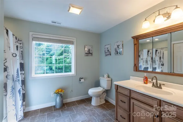 a bathroom with a sink mirror toilet and next to a window