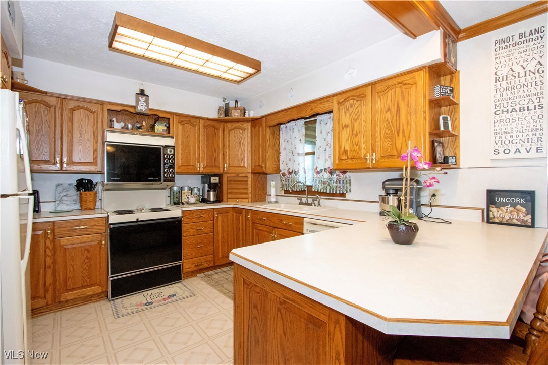 1292 Cinder Road Southeast Carrollton, OH 44615 - Photo 24 of 42 Kitchen with white appliances, open shelves, a peninsula, light countertops, and light flooring