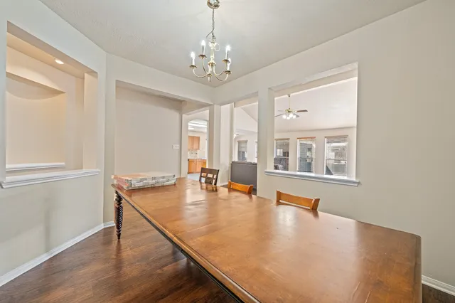 a dining room with wooden floor a chandelier a glass table and chairs