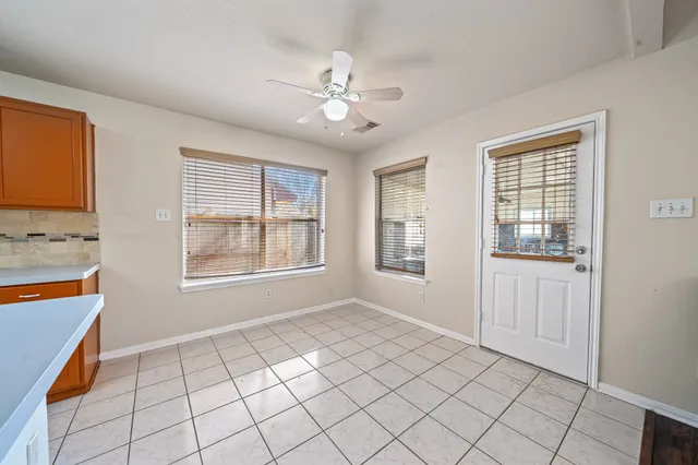 a view of an empty room with window and cabinet area