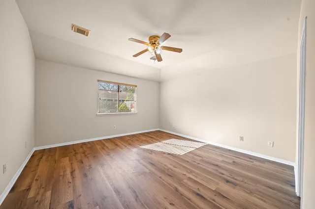 a view of empty room with wooden floor and fan
