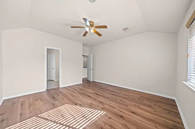a view of empty room with wooden floor and fan