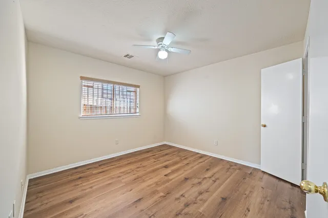 a view of a room with wooden floor and a ceiling fan