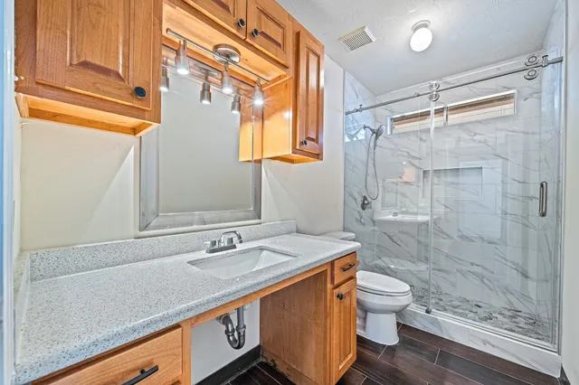 a bathroom with a sink a toilet a mirror and shower